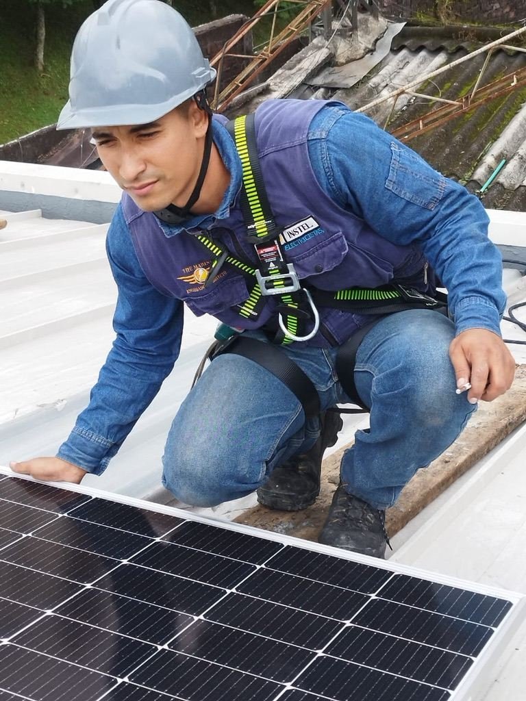 Técnico de Instel Company instalando un panel solar con arnés de seguridad