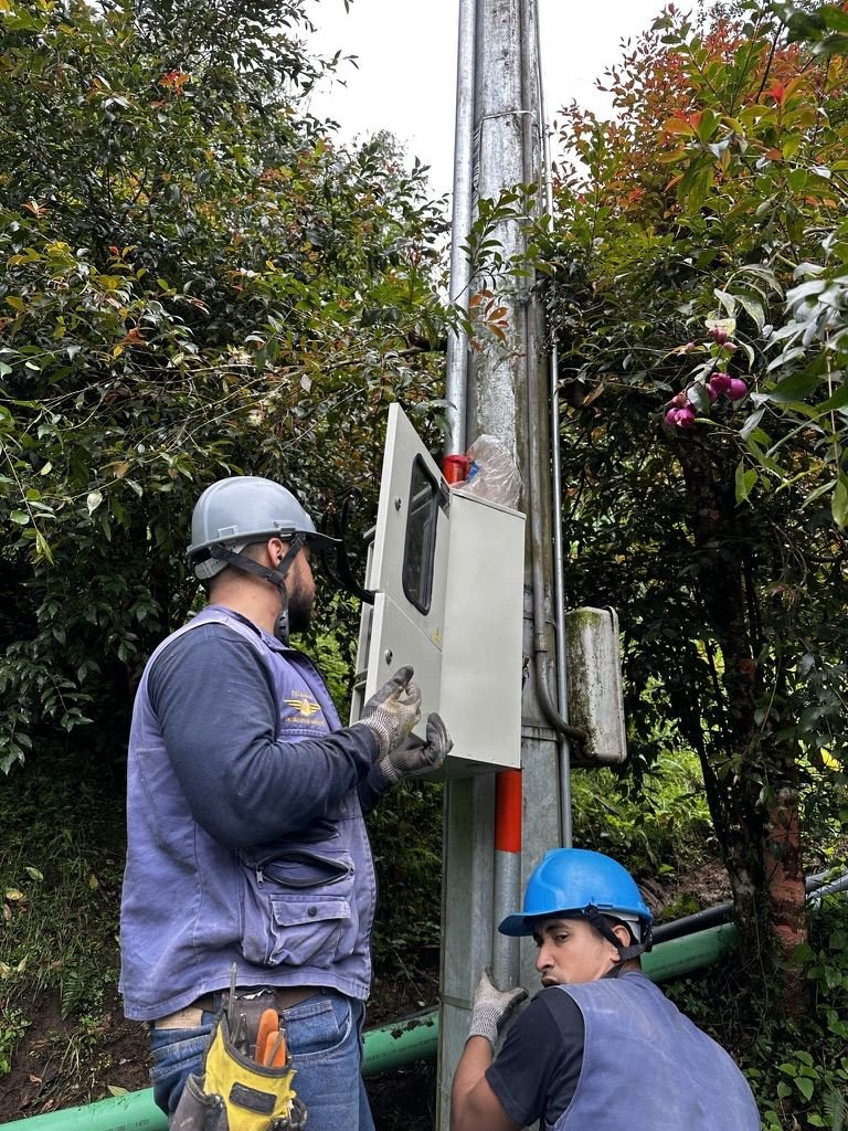 Técnicos de Instel Company instalando gabinete eléctrico sobre poste